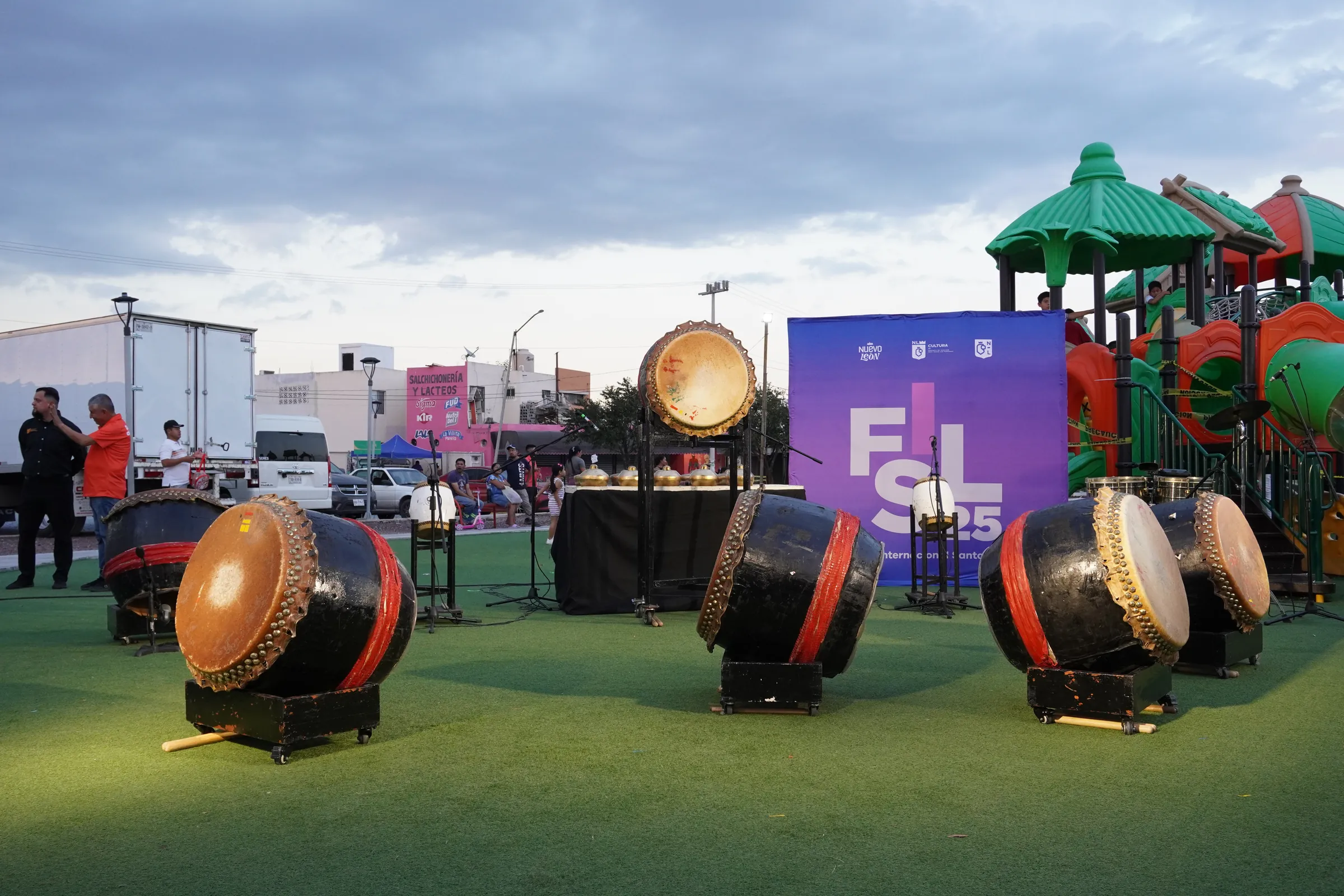 Los tambores del grupo, listos en la cancha al atardecer, con el escenario del festival al fondo
