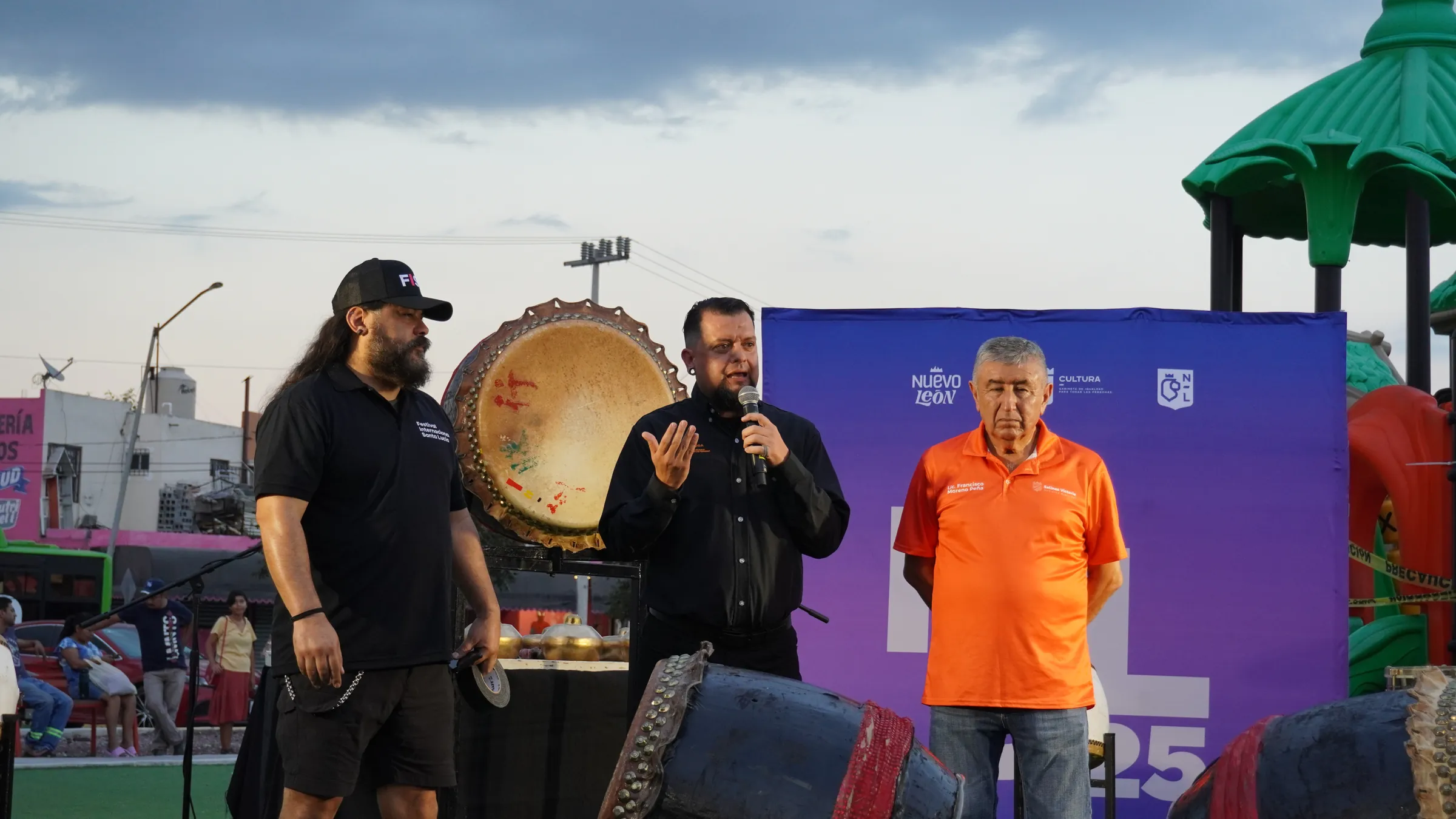 Presentadores y organizadores en el escenario, frente a los tambores