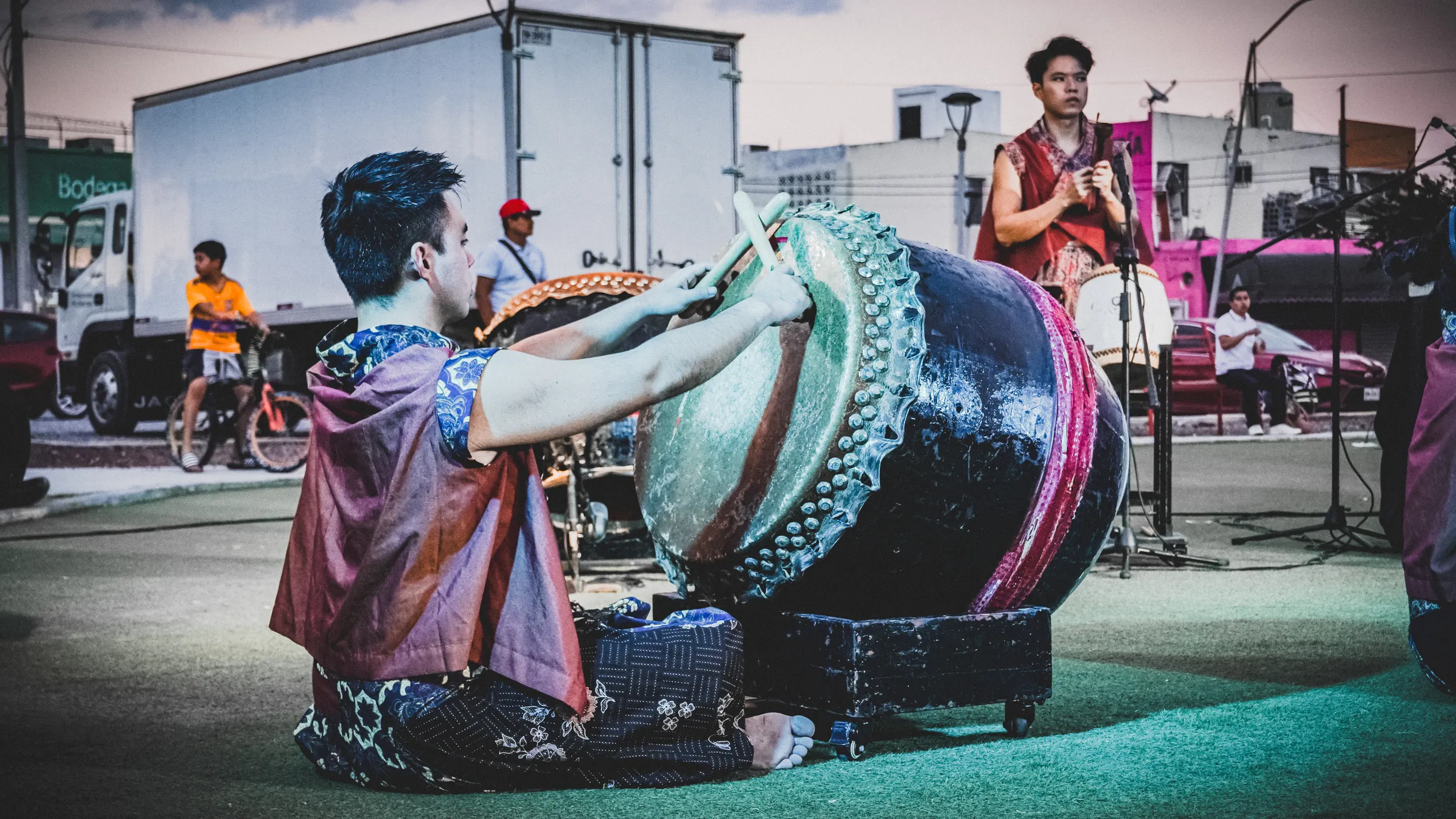 Un percusionista sentado frente al tambor, con los camiones de fondo