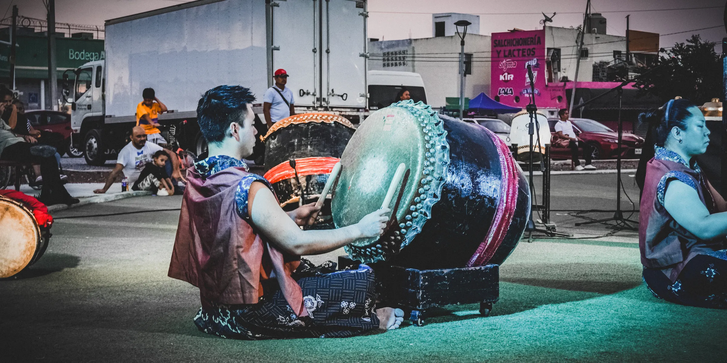 Percusionistas tocando sentados en el piso de la cancha