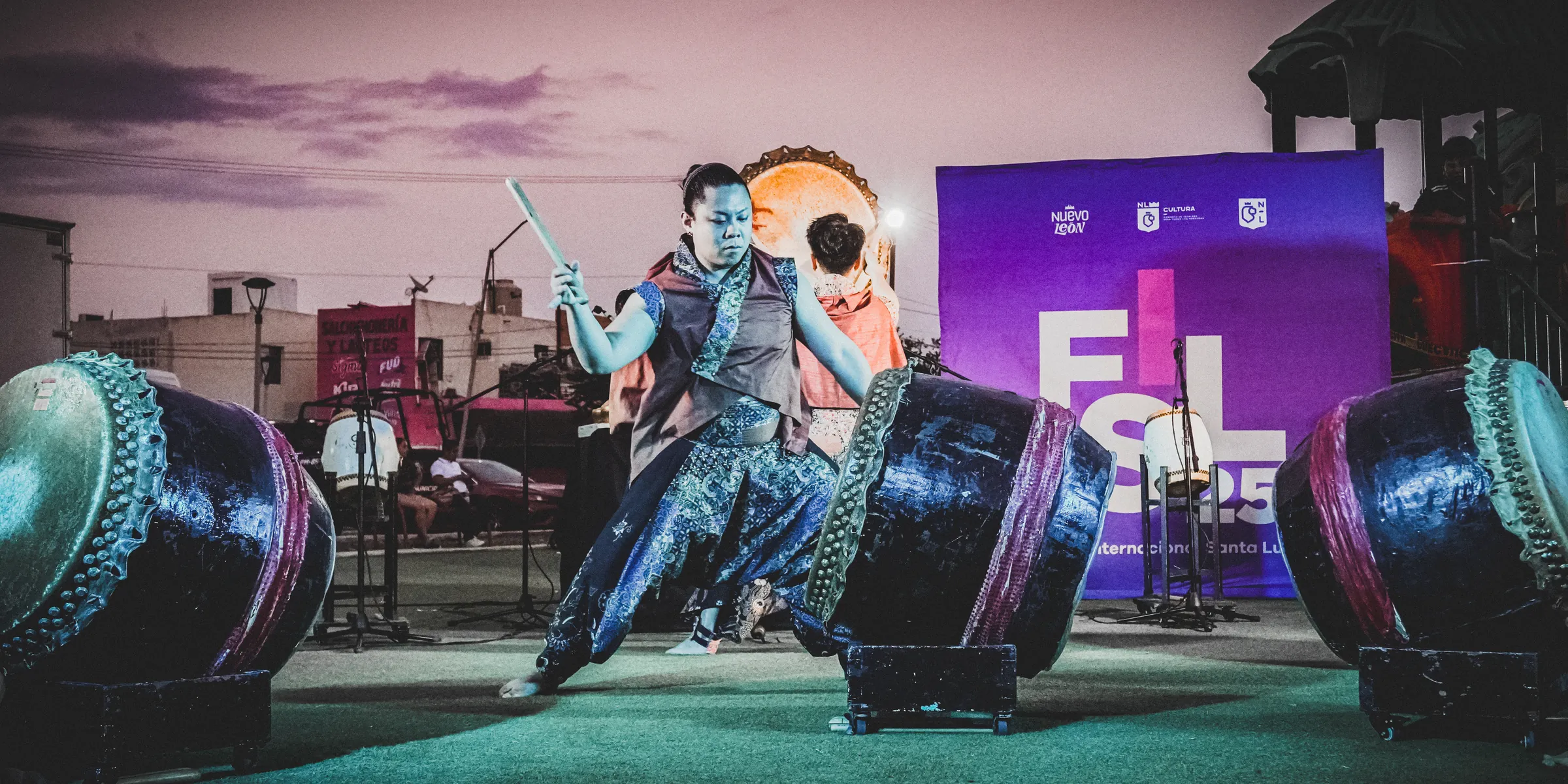 Un percusionista con los brazos arriba frente al logo del festival