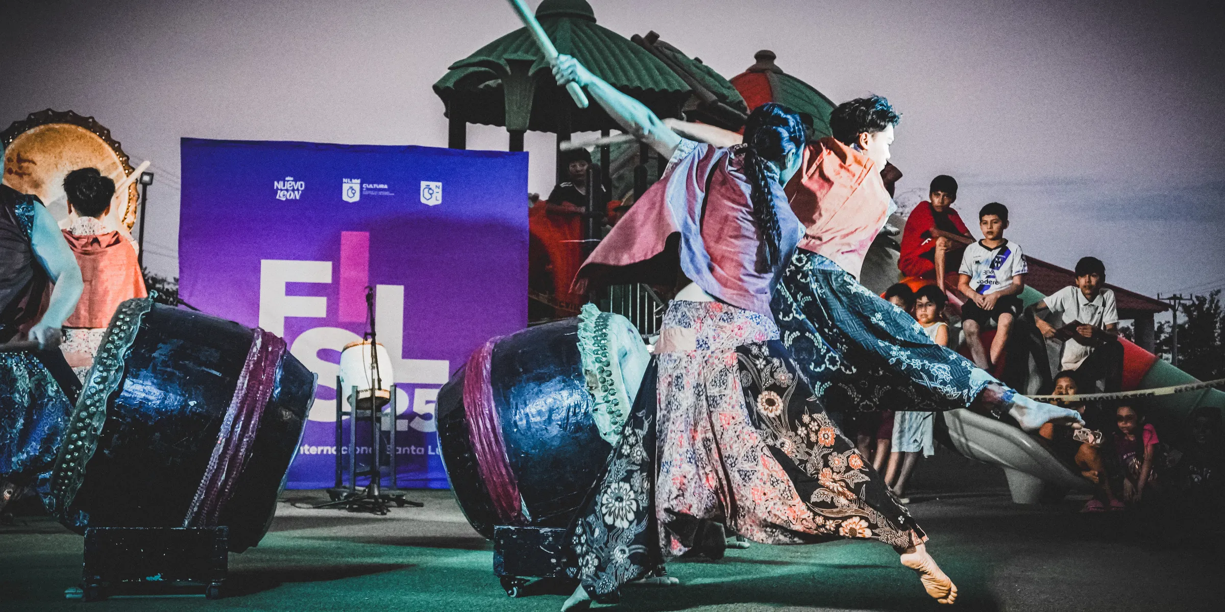 Una bailarina con tela de batik se lanza hacia adelante entre los tambores