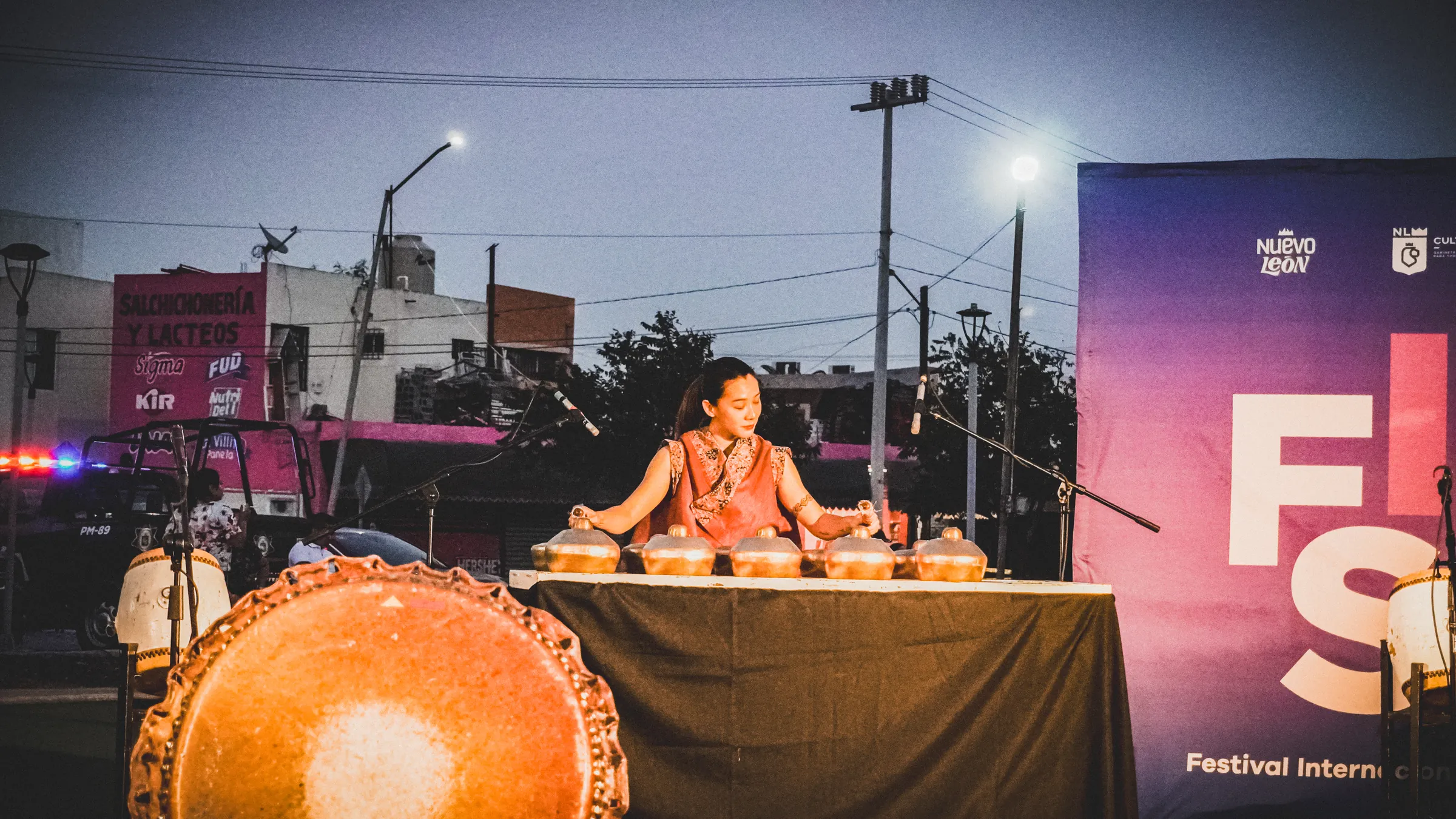 Una percusionista toca los tambores pequeños frente a la pantalla del festival, ya de noche