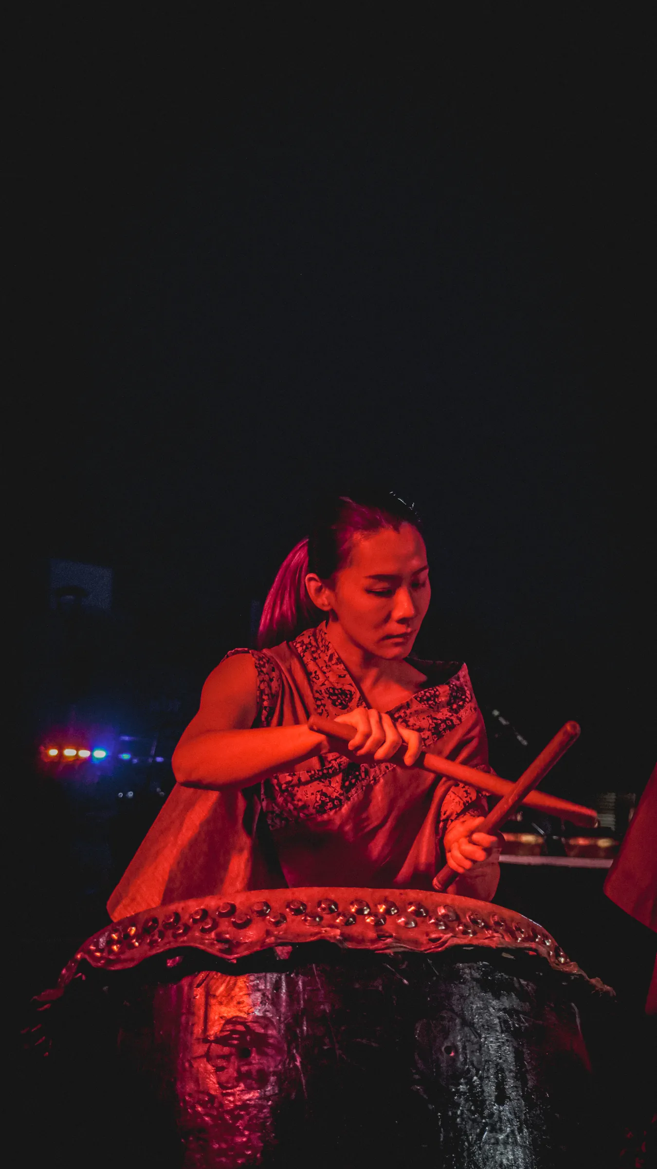 Una percusionista iluminada en rojo toca el tambor