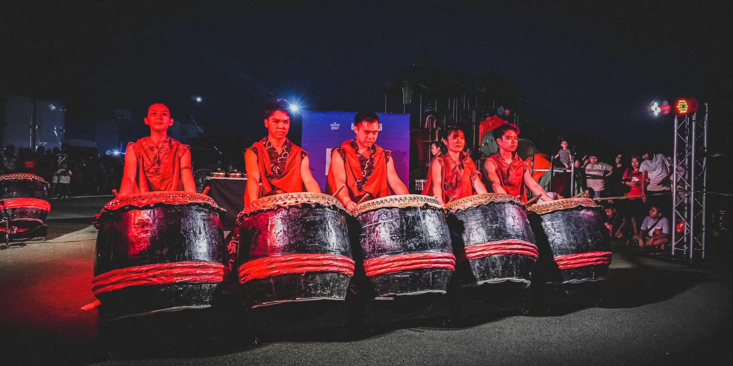 La fila de tambores bajo luz roja, con el grupo tocando al mismo tiempo