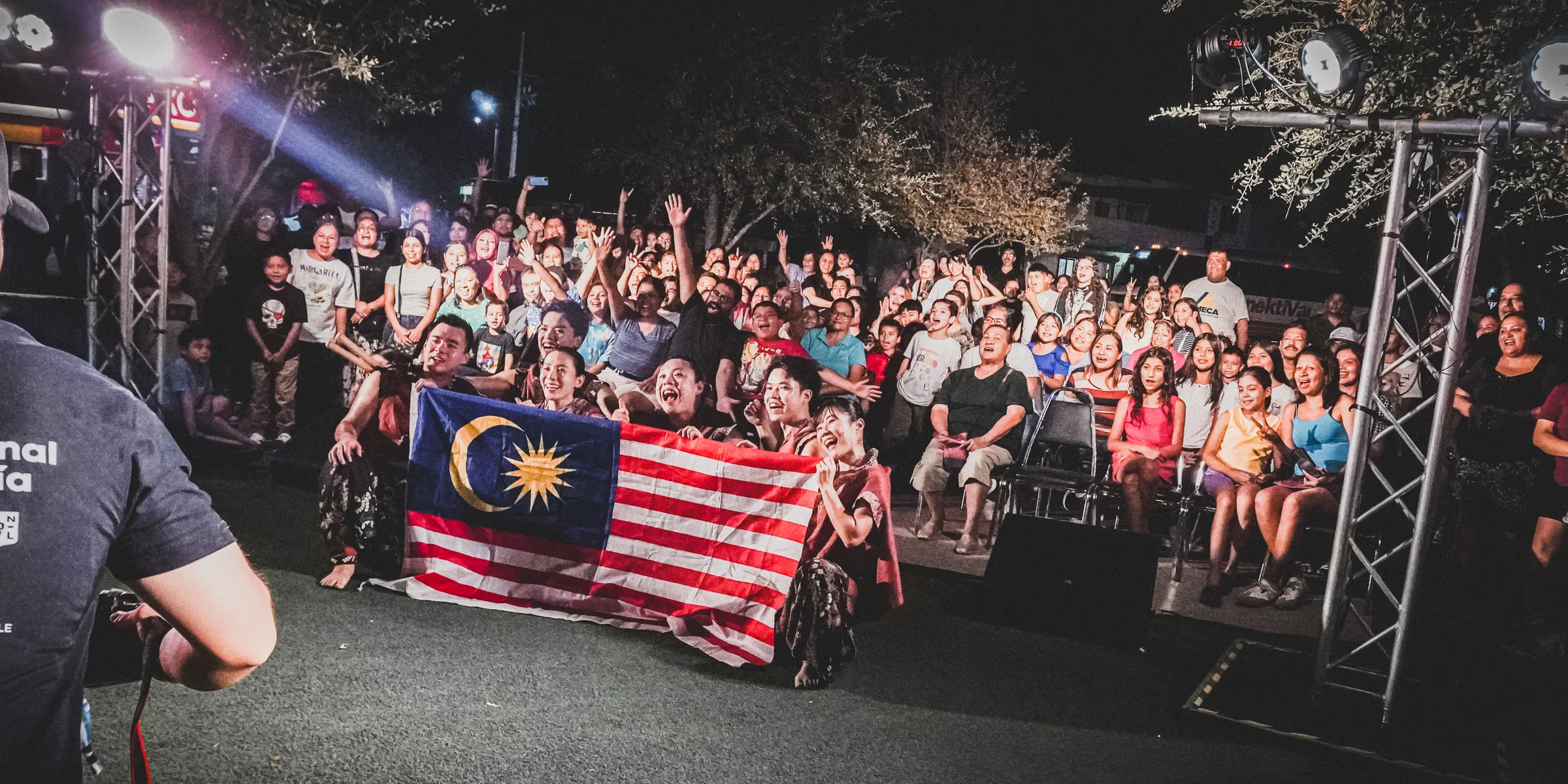 El público sostiene la bandera de Malasia frente al escenario