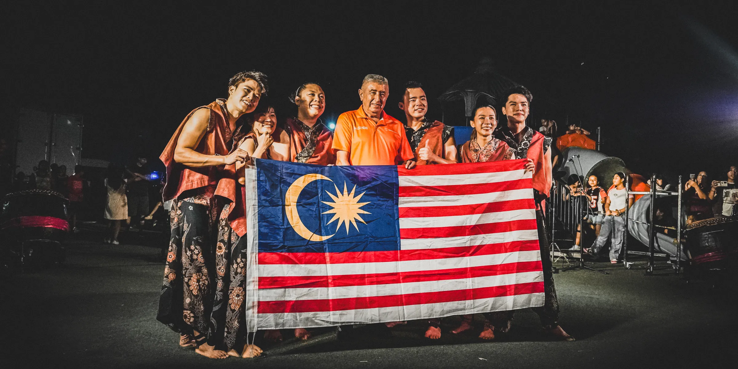 El grupo con la bandera de Malasia al final de la presentación
