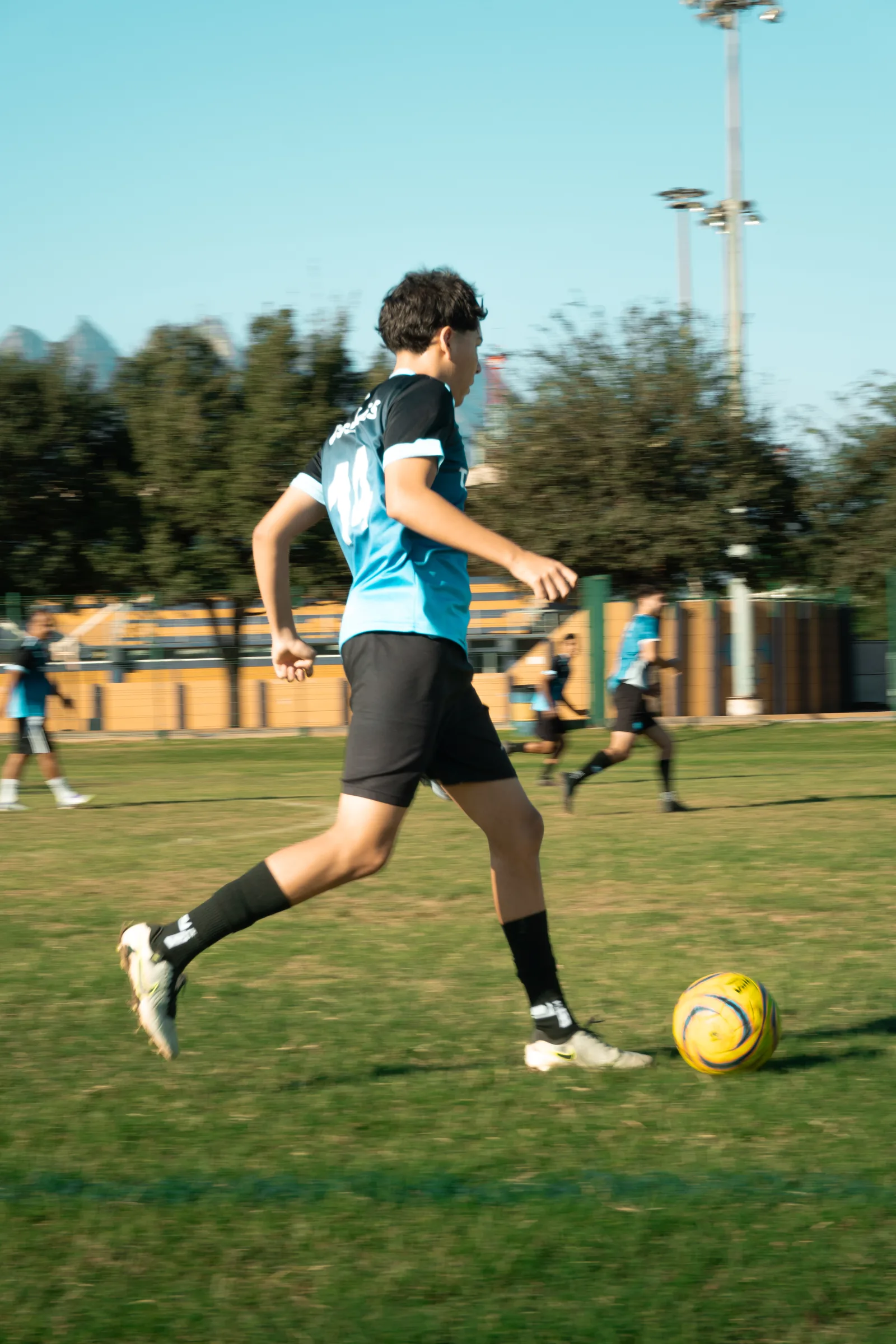 Un jugador de Tucanes corre con el balón, con el Cerro de la Silla y las gradas del campo detrás