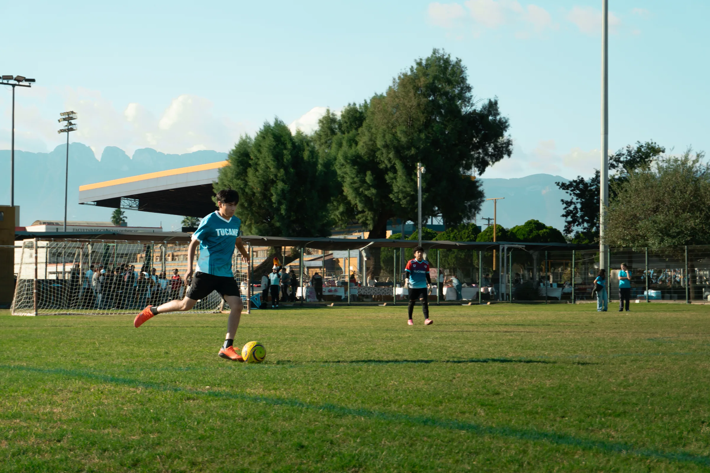 Un jugador de Tucanes dispara hacia la portería, con las instalaciones de Ciudad Universitaria al fondo