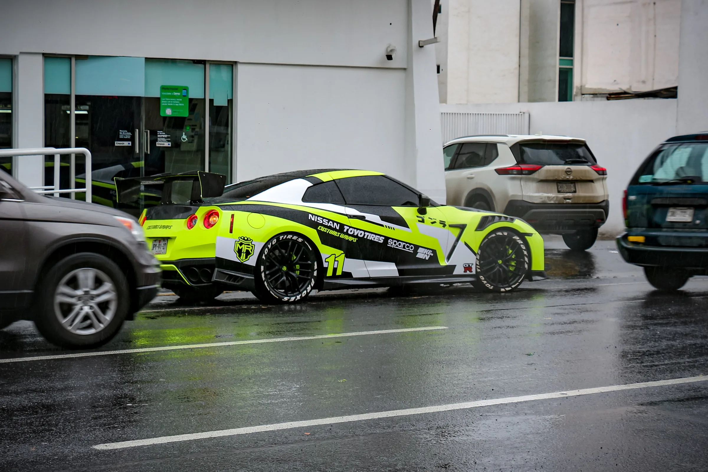 El GT-R de tres cuartos trasero, con el alerón y el difusor negro entre el tráfico