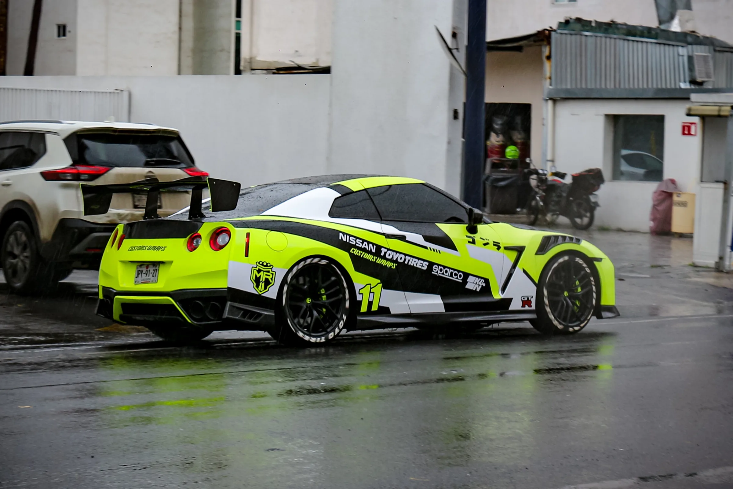 El GT-R alejándose por la calle mojada, visto desde atrás