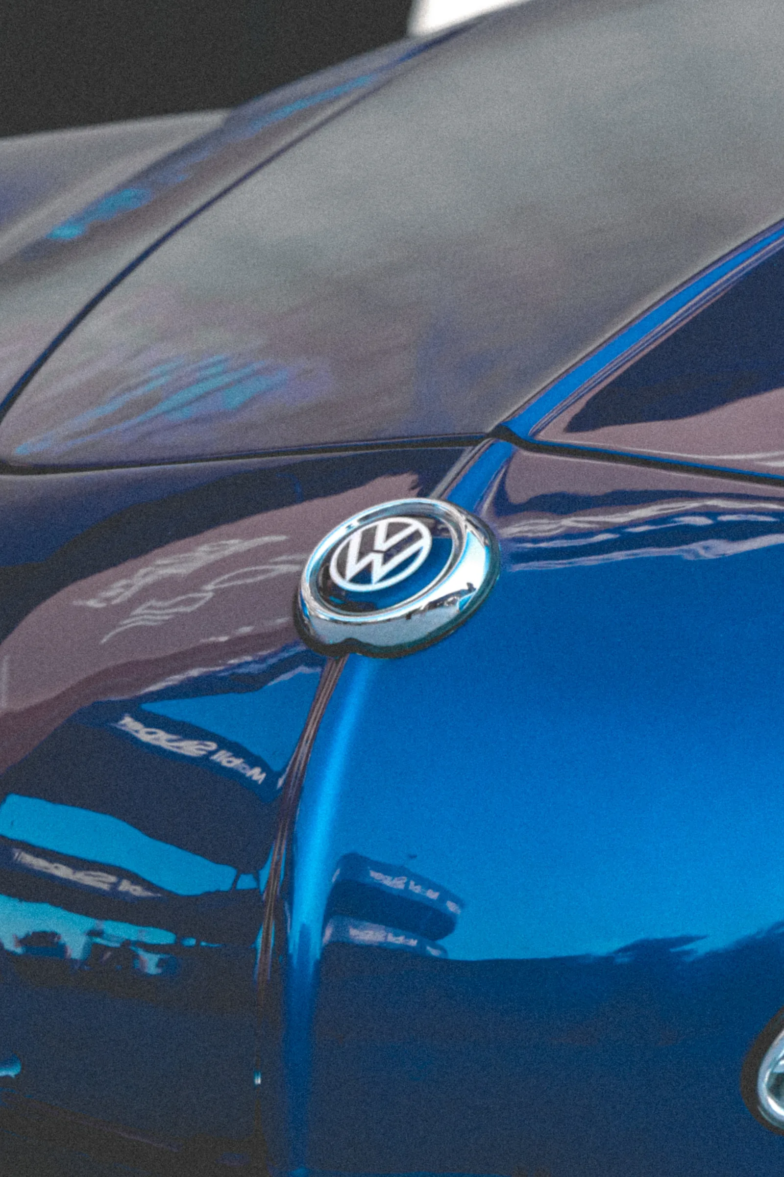 Acercamiento al emblema de Volkswagen sobre el cofre azul del Karmann Ghia